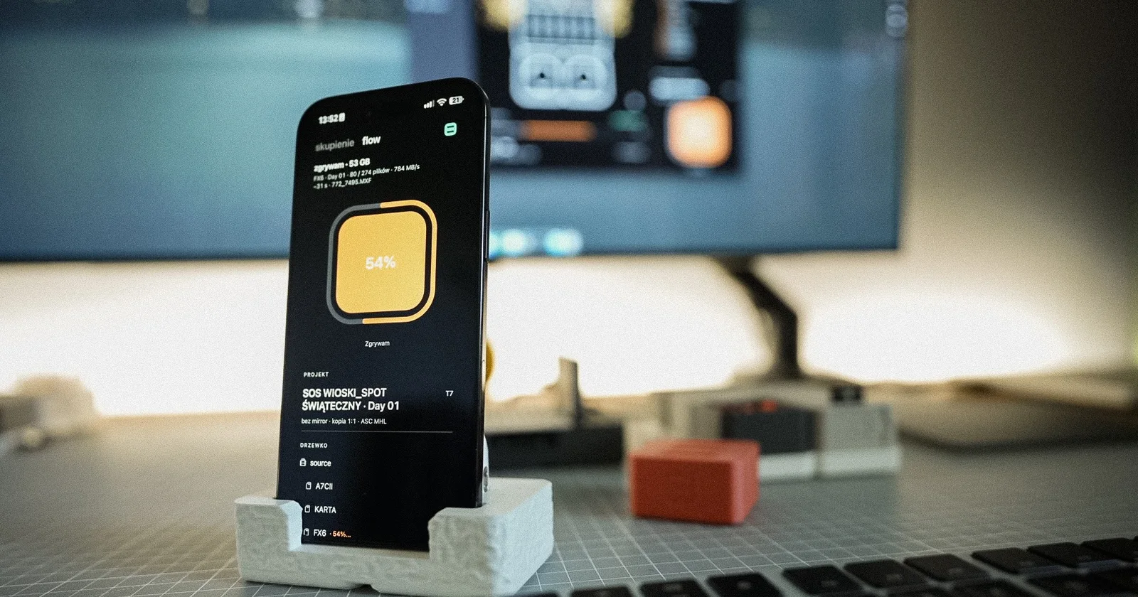 iPhone in a stand by the keyboard, Habitat Flow showing ingest at 54%, Mac behind